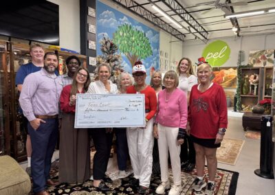 Group of people holding a large check indoors, smiling at the camera.