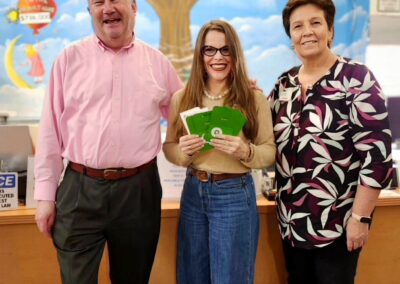 Three people smiling together in a bright room with a colorful background.