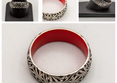 Silver ring with intricate cutout design and red interior lining.