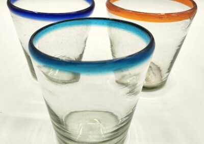 Three clear glasses with colored rims in blue, green, and orange.
