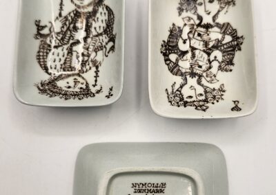 Three vintage ceramic dishes with black illustrations and a signature on the bottom one.