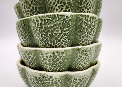 Stack of green ceramic bowls with textured, crackled glaze.