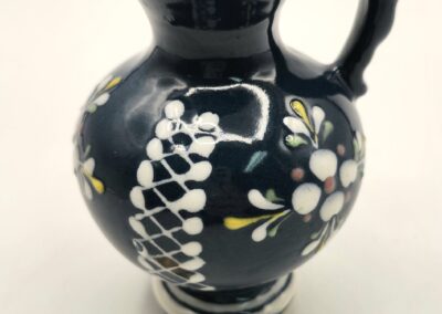 Black ceramic jug with floral and geometric patterns.