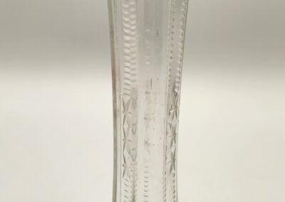 Tall glass vase with intricate vertical patterns and a slightly flared rim.