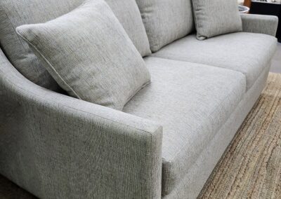 Modern gray fabric sofa with plush cushions on a woven rug.