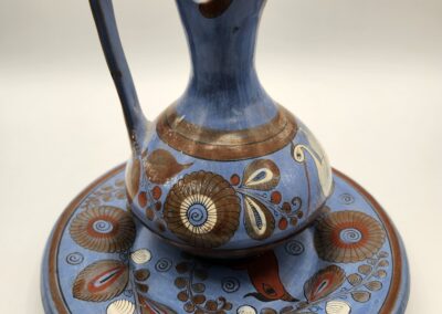 Decorative ceramic pitcher with matching plate in blue and brown patterns.