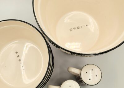 Vintage enamelware bowls and salt and pepper shakers on a countertop.