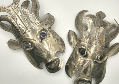 Close-up of two ornate silver animal head sculptures with blue gem eyes.