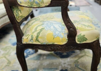 Vintage wooden chair with floral upholstery and curved armrests.