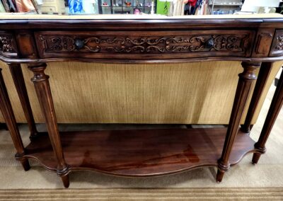 Ornate wooden console table with intricate carvings and lower shelf.