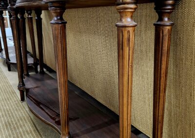 Elegant wooden console tables with carved legs and lower shelves.