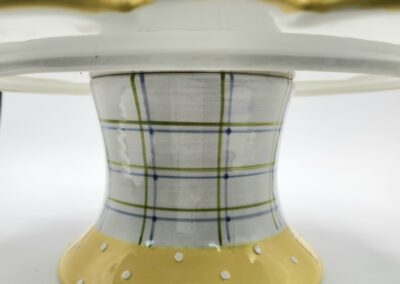 A ceramic cake stand with a plaid pattern and polka dot base.