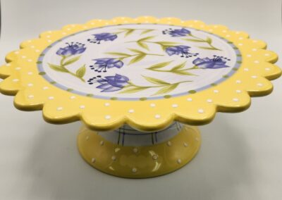 Yellow polka dot cake stand with floral design on top.