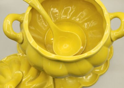 Bright yellow ceramic pumpkin-shaped soup tureen with lid and ladle.
