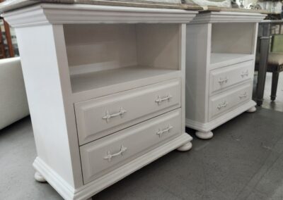 Two white wooden nightstands with drawers and open shelves.