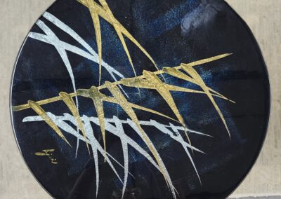 Abstract circular artwork with gold, white, and blue streaks on a dark background.
