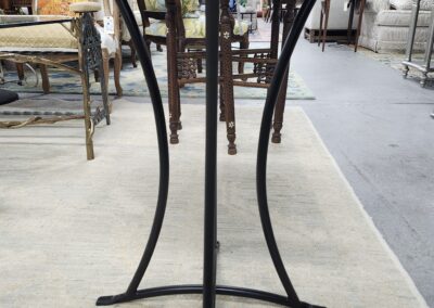 Metal table base with curved legs on a workshop floor.