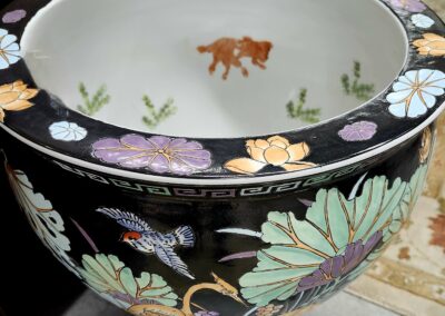 Ornate round planter with floral designs and a goldfish inside.