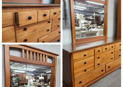 Wooden dresser with multiple drawers and a large mirror in a furniture store.