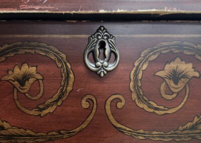 Close-up of an ornate wooden drawer with floral and swirl designs.