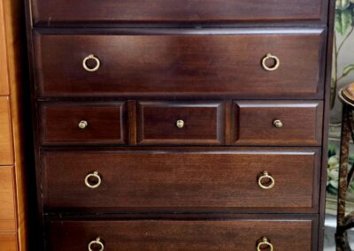 Dark wooden dresser with multiple drawers and ring handles.
