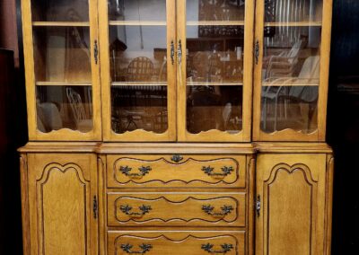 Vintage wooden cabinet with ornate handles and glass-paneled upper doors.