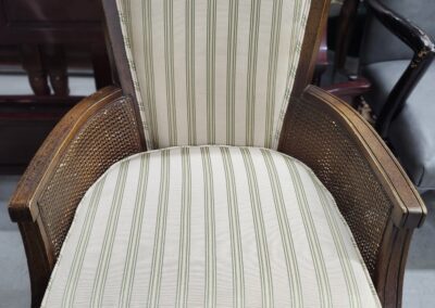 Antique wooden armchair with striped upholstery and carved details.