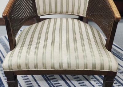 Elegant wooden chair with striped upholstery and curved armrests.