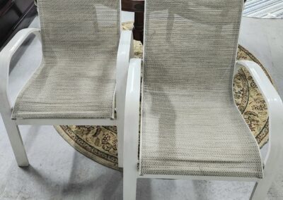 Two white plastic chairs with worn-out seats placed on a circular rug.