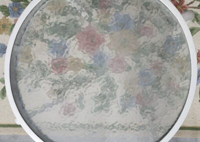 A magnifying glass focusing on a detailed floral pattern on fabric.