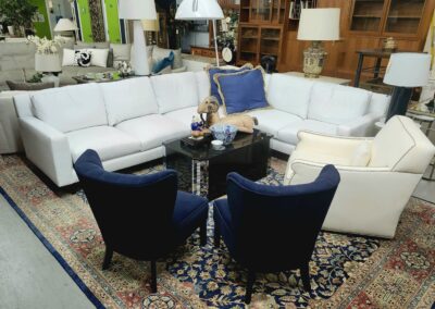 Cozy living room with white sofas and blue armchairs around a glass coffee table.
