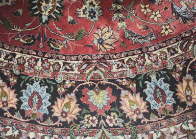 Intricately patterned red and black rug with floral motifs.