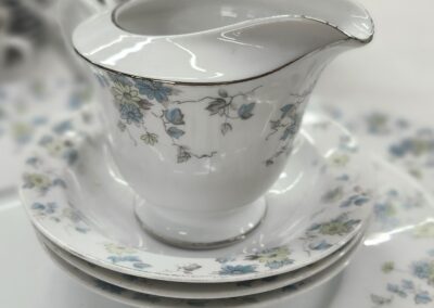 Elegant porcelain creamer with floral design on matching saucer.