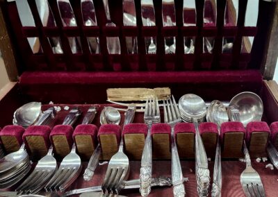 A collection of vintage silverware and cutlery displayed on a wooden rack.