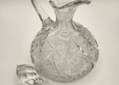 Clear glass decanter with a textured pattern and stopper beside it.