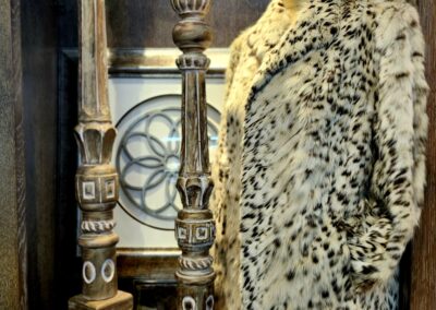 Luxurious leopard-print fur coat displayed near ornate antique clock.