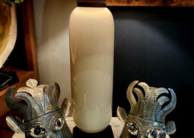 Two metallic ram sculptures beside a tall ceramic lamp.