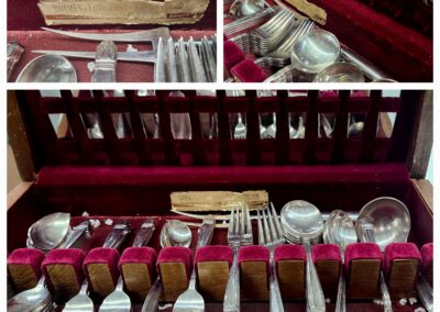 Vintage silverware set displayed in a wooden case with red lining.
