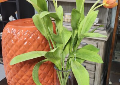 Green leafy plant in front of an orange textured vase.