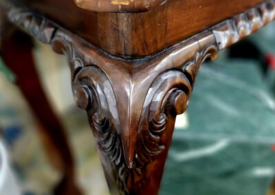 Close-up of an intricately carved wooden table leg with ornate details.