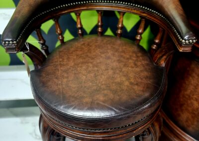 Antique leather swivel chair with detailed woodwork.