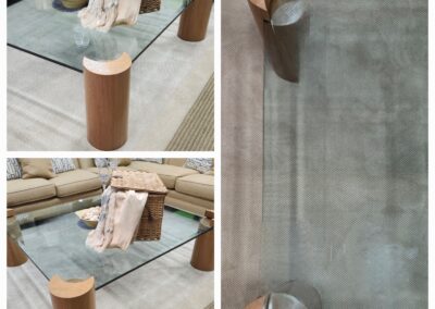 Modern glass coffee table with cylindrical wooden legs and minimalist design.