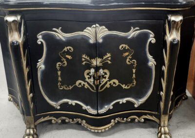 Elegant black and gold vintage cabinet with ornate designs and claw feet.