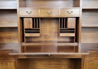 Wooden desk with drawers and a built-in hutch, flanked by empty bookshelves.