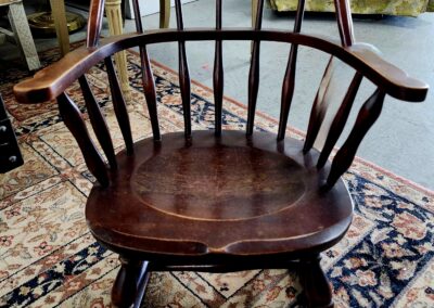 Wooden Windsor chair with curved back and spindles on a patterned rug.