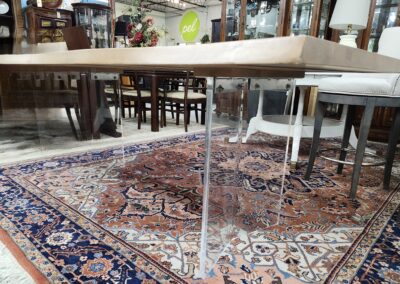 Clear acrylic legs supporting a wooden table on a patterned rug.