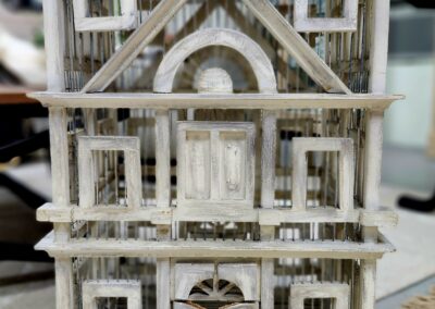 Detailed miniature wooden model of a Victorian-style house with intricate windows and door.