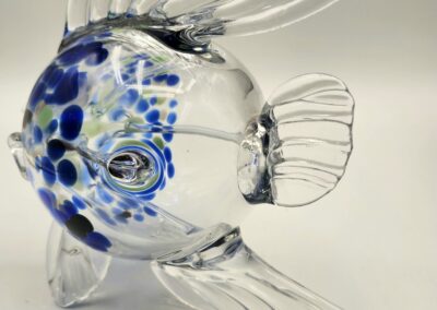 A glass fish sculpture with blue spots and clear fins.