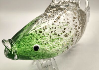 A green and clear glass fish sculpture with speckled details.