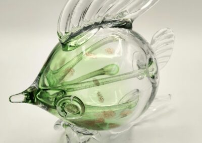 A delicate glass fish sculpture with green and clear hues.